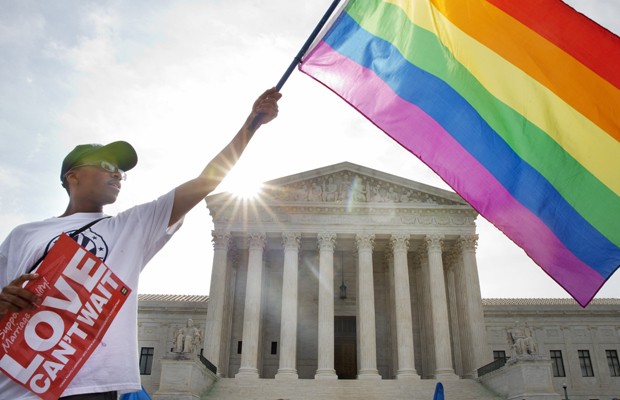 Ativista Carlos McKnight levanta bandeira do movimento GLBT em frente à Suprema Corte em Washington, nesta sexta (26), após a aprovação do casamento entre homossexuais em todo o país (Foto: Jacquelyn Martin/AP)